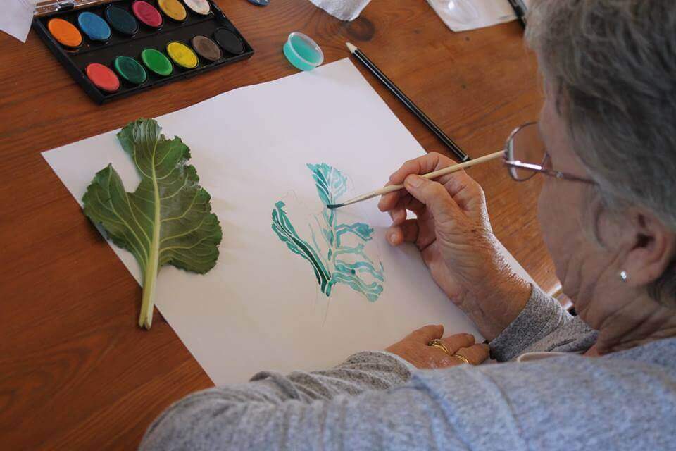 An adult painting a leaf with water-colours
